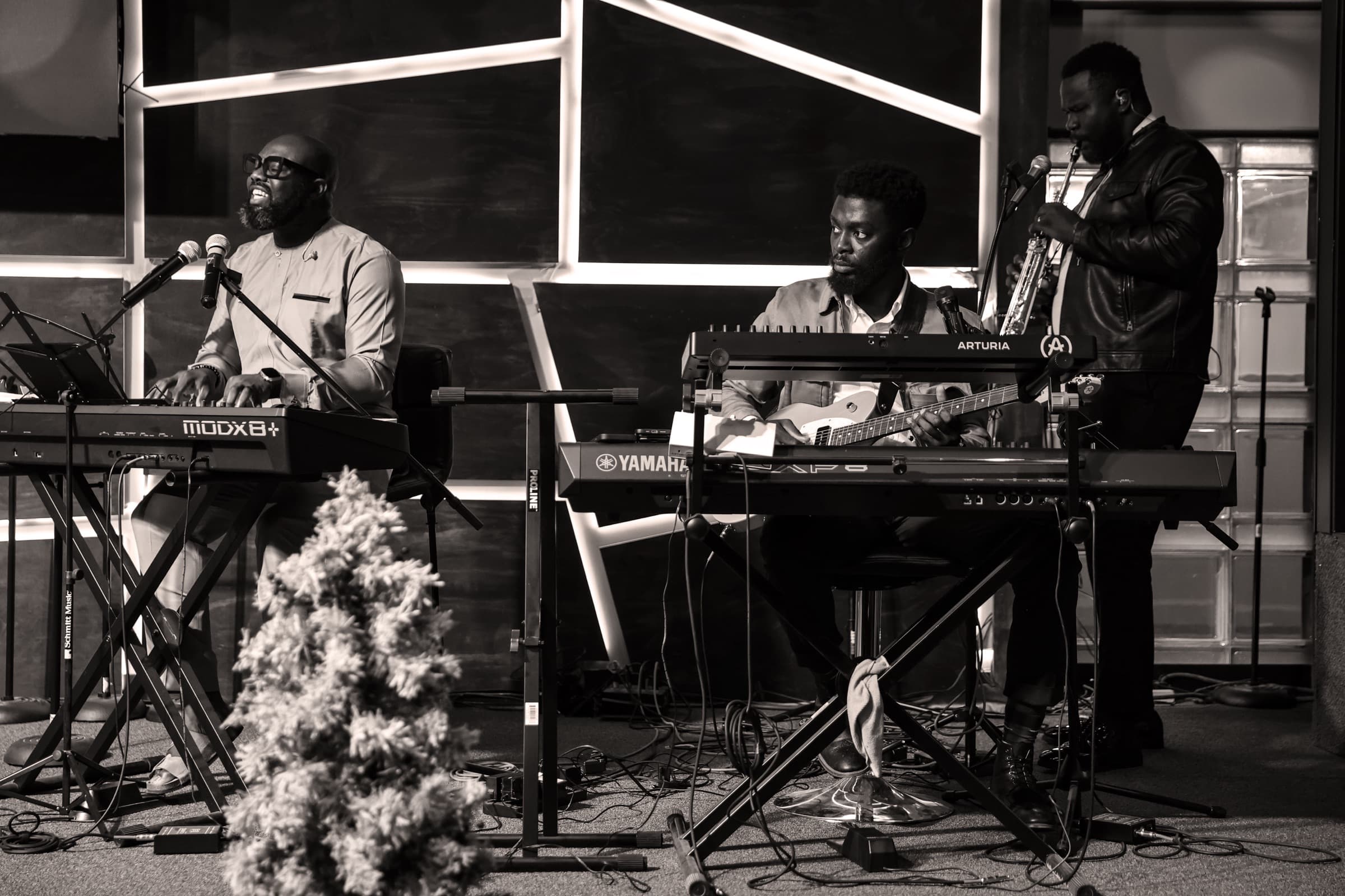 The church band — keys, guitar, and saxophone — leading worship, in black and white